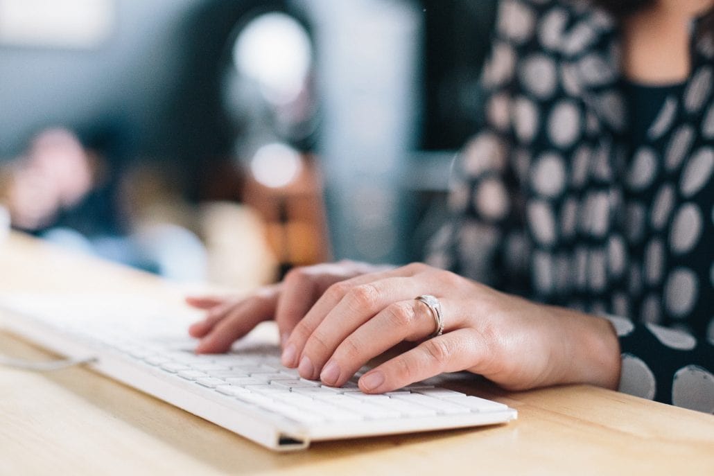 A millennial manager typing on a computer keyboard.